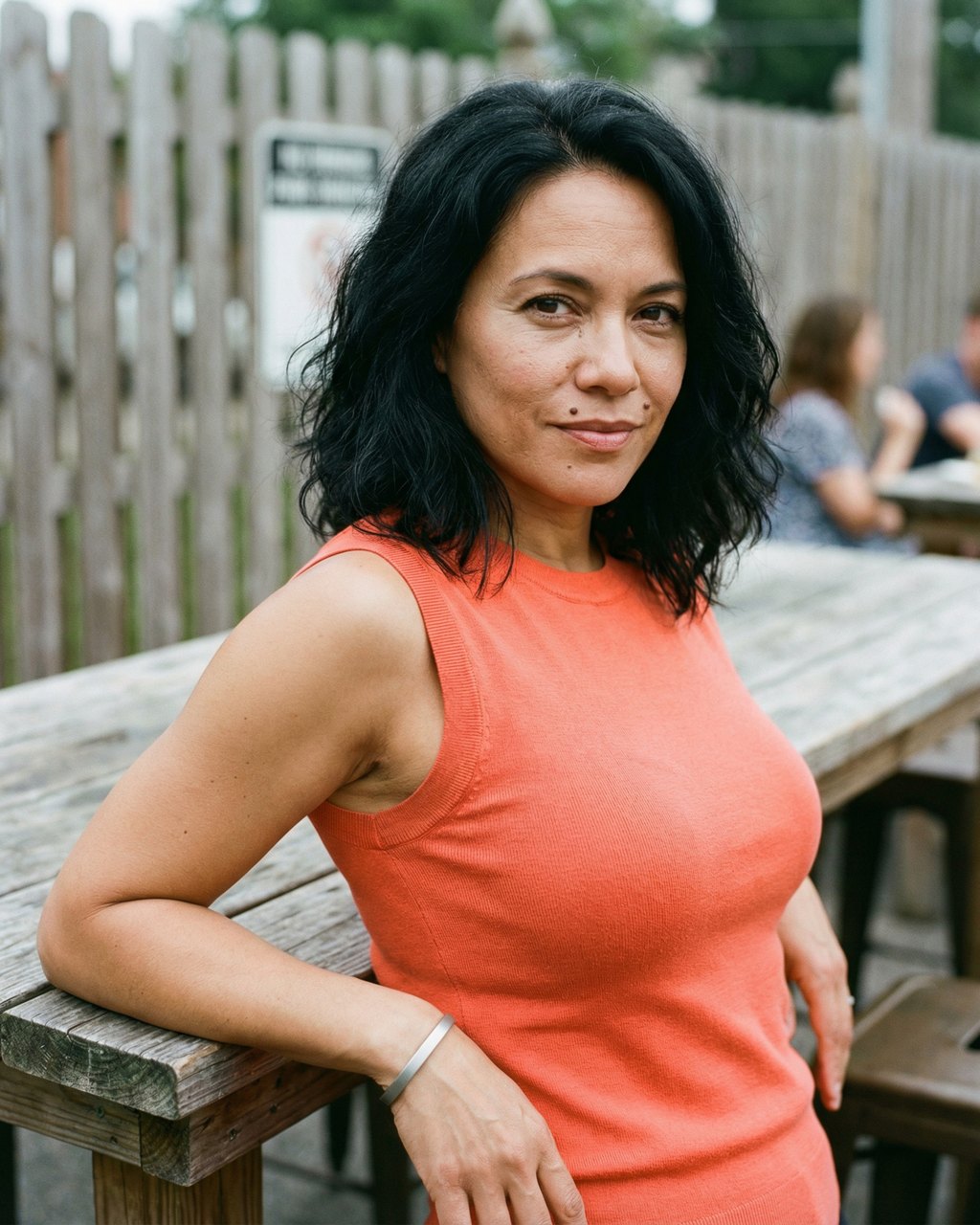 Calm Half-Smile in a Coral Sleeveless Knit Top