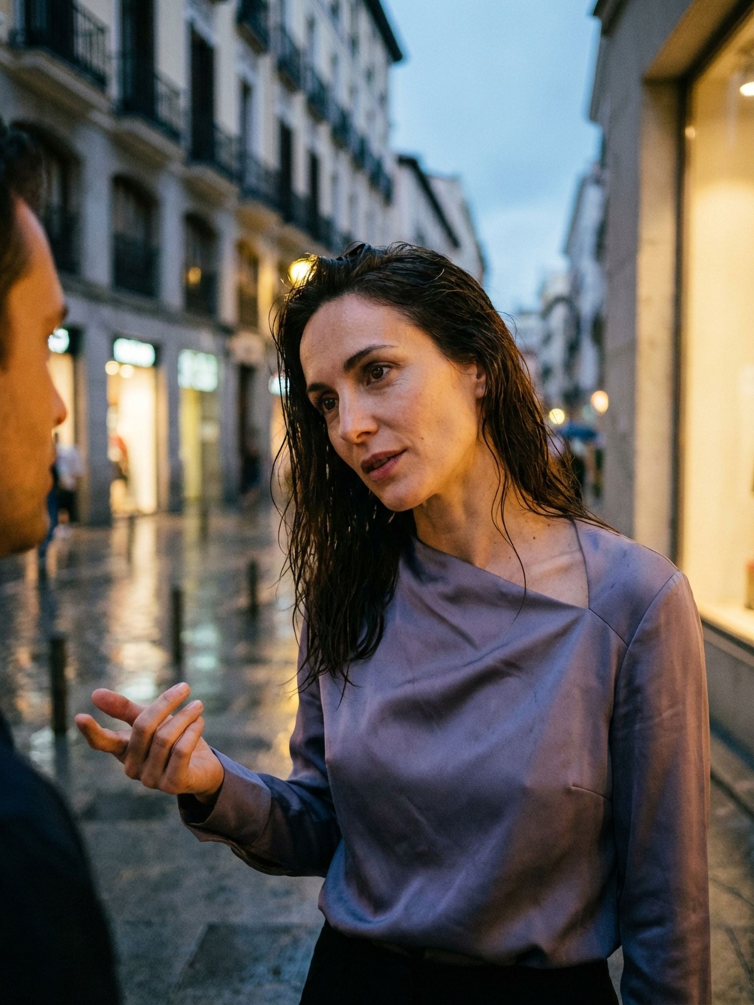 Rain-washed street conversation under soft evening window light
